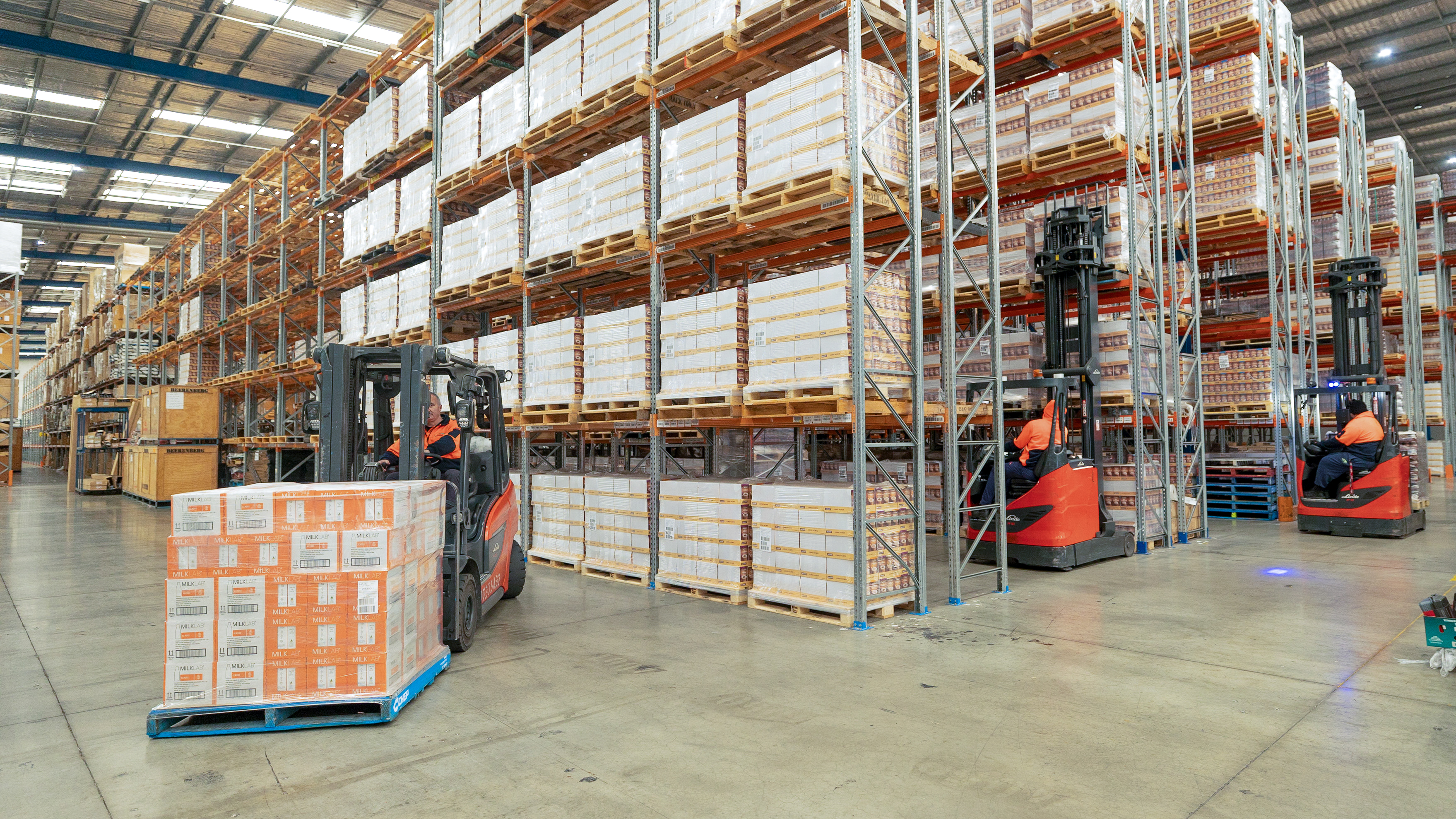 Red Linde engine forklift and reach truck performing warehouse operations