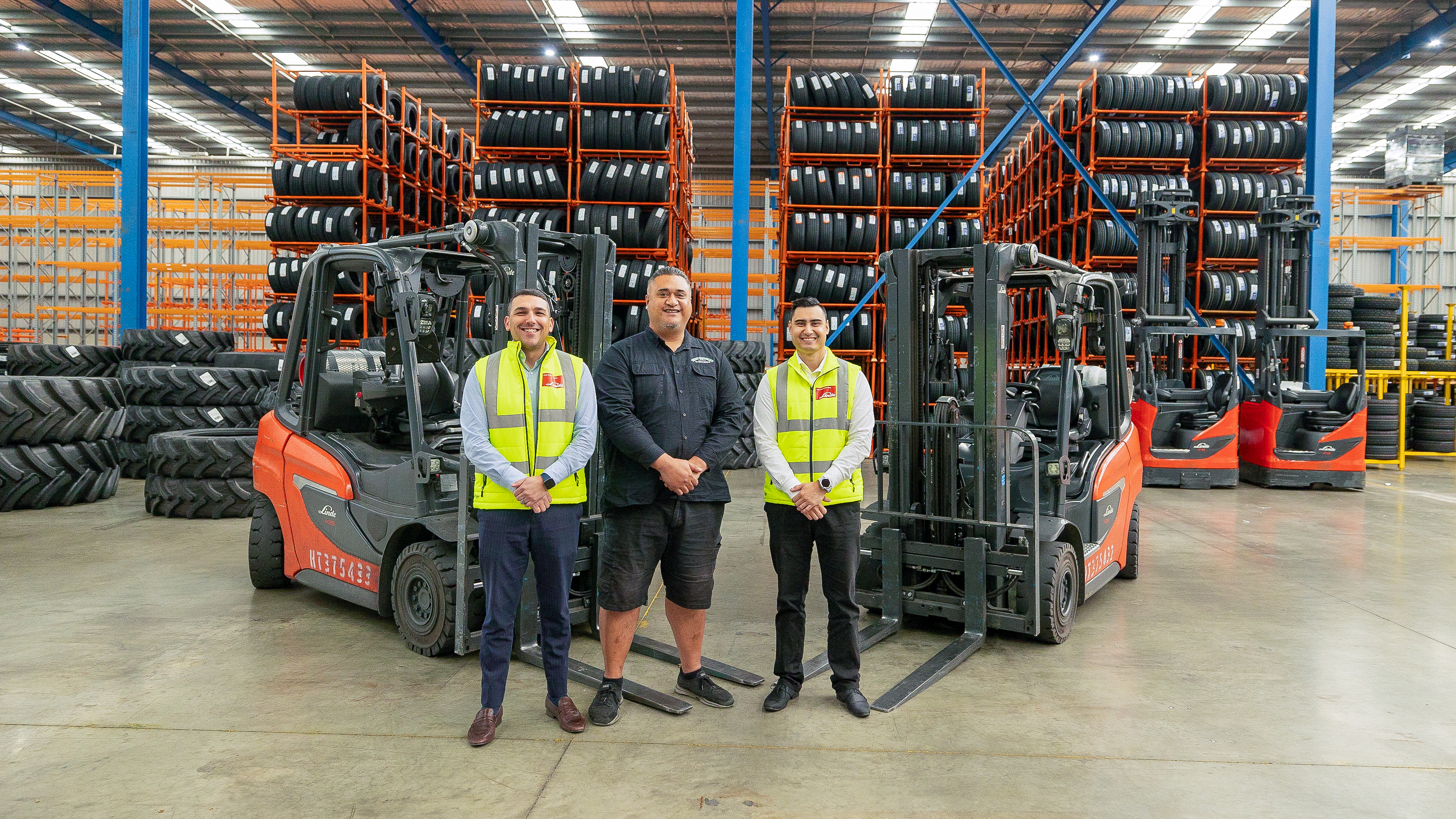 Sales persons from Linde delivering red engine forklifts and reach trucks