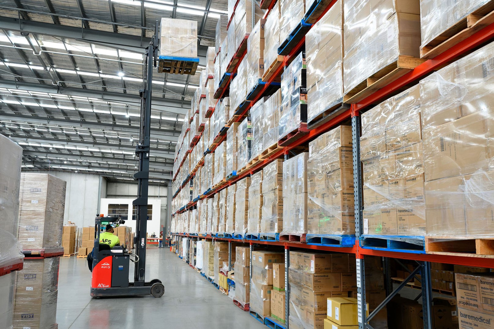 A red reach truck busy with shelving operations at a Linde customer site